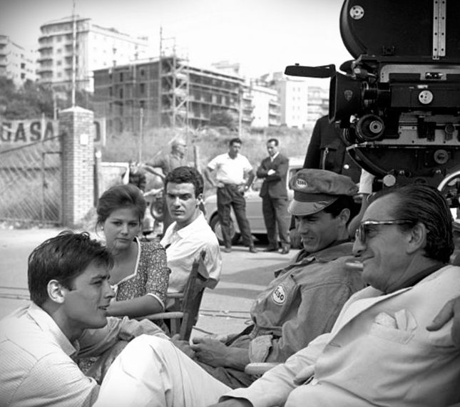 Luchino Visconti sul set milanese di «Rocco e i suoi fratelli», 1960, con gli attori e i cantieri della città sullo sfondo