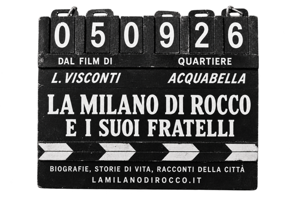Un ciak da cinema, in bianco e nero. In alto la data «05 09 26»; sotto, le scritte «Dal film di L. Visconti» e «Quartiere: Acquabella»; al centro, grande, il titolo «La Milano di Rocco e i suoi fratelli»; in basso «Biografie, storie di vita, racconti della città» e l'indirizzo lamilanodirocco.it.
