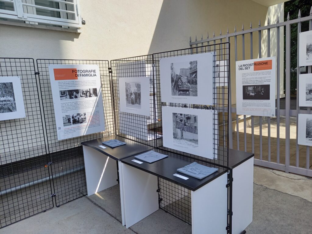 Angolo della mostra con i pannelli "Fotografie di famiglia" e "La ricostruzione del set"; su un tavolo, le tavole tattili