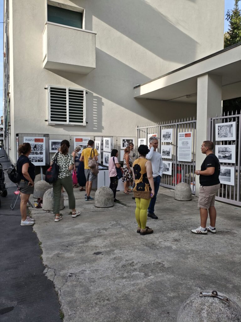 Un gruppo di visitatori osserva le fotografie lungo la cancellata.